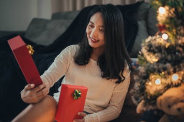 Bir kadın Noel günü sürpriz yapıp hediye kutusuna bakıyor. Noel hediyeli mutlu kız evde Noel 'i kutluyor..