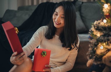 Bir kadın Noel günü sürpriz yapıp hediye kutusuna bakıyor. Noel hediyeli mutlu kız evde Noel 'i kutluyor..