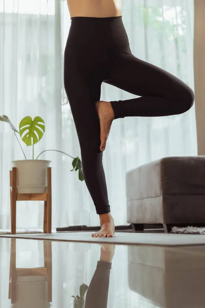 Young woman practicing yoga at home. Fit woman in sportwear doing yoga online at home in living room.