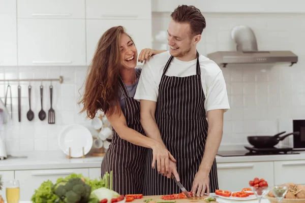 Happy couple love cooking together in kitchen. Young loving man and woman laughing while cooking healthy food at home.
