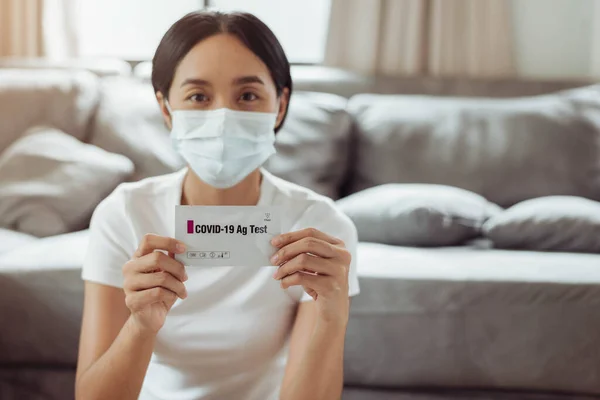 Young woman self test for COVID-19 at home with antigen kit. asian woman using coronavirus covid-19 rapid antigen home testing kit, Coronavirus nasal swab test for infection.