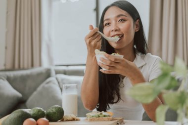 Sağlıklı kadın sağlıklı yemek yiyor. Evde sağlıklı yemek pişiren genç bir kadın. Sağlıklı ve sağlıklı olma kavramı.