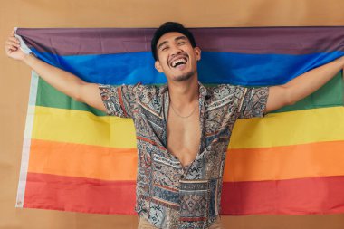 Mutlu adam gülümsüyor ve gurur bayrağıyla ayakta duruyor. Cinsiyet Eşitliği ve LGBTQ kavramı.