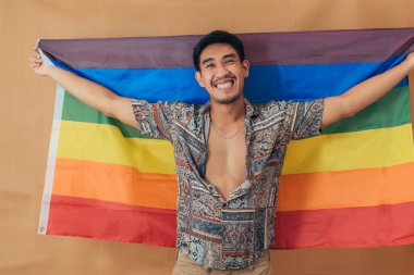 Mutlu adam gülümsüyor ve gurur bayrağıyla ayakta duruyor. Cinsiyet Eşitliği ve LGBTQ kavramı.