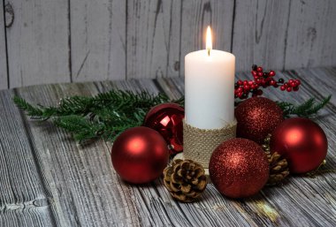 Balmumu koniler, köknar dalları ve ahşap arka planda kırmızı toplar.