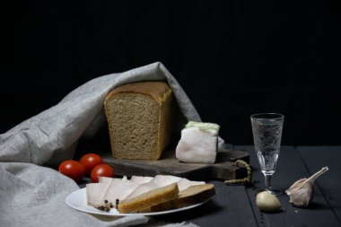 Bir somun ekmek, dilimlenmiş domuz yağı ve sarımsak peçeteye.