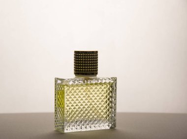 Arka planda dikdörtgen bir parfüm şişesi. Oluklu cam.