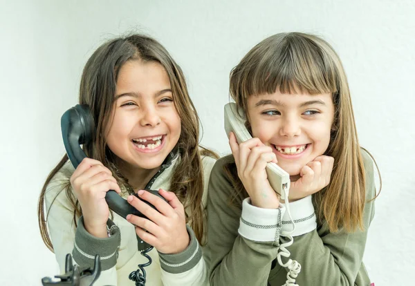 Two seven year old girls talking on the old vintage phones with