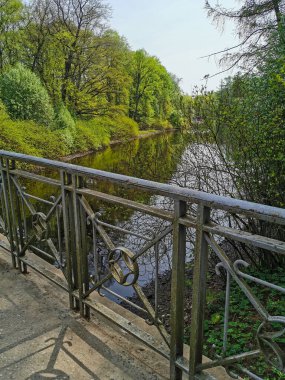 St. Petersburg 'daki Elagin Adası' ndaki parkta güneşli bir bahar gününde kanalın üzerindeki köprünün çiti..