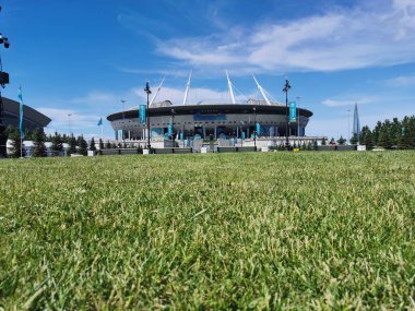 EURO 2020 Avrupa Futbol Şampiyonası 'nın olduğu sabah St. Petersburg' daki Gazprom Arena Stadyumu 'nun önündeki çimen ve banklar bulutlu mavi gökyüzüne karşı..