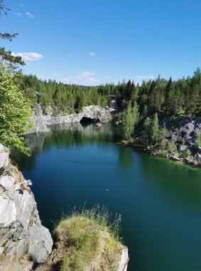 Ruskeala Dağ Parkı 'ndaki Mermer Kanyon' un turkuaz suyunun gözlem güvertesinden gökyüzünün yansıması ve güneşli bir yaz gününde ağaçların görüntüsü..