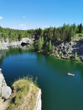 Ruskeala Dağ Parkı 'ndaki Mermer Kanyon' un turkuaz suyunun gözlem güvertesinden gökyüzünün yansıması ve güneşli bir yaz gününde ağaçların görüntüsü..
