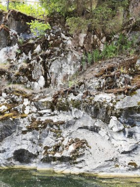 Güneşli bir yaz gününde Ruskeala 'daki dağ parkındaki Mermer Kanyon' da bazen yosun ile kaplanmış mermer sudan manzara