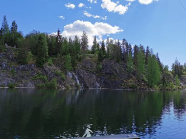Güneşli bir yaz gününde Ruskeala Dağ Parkı 'nda ağaçların yetiştiği su basmış Mermer Kanyon' un yanındaki yüzer platformdan bir manzara..