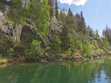 Güneşli bir yaz gününde Ruskeala Dağ Parkı 'ndaki Mermer Kanyon' un kayalık kıyıları ve zümrüt suyu manzarası.