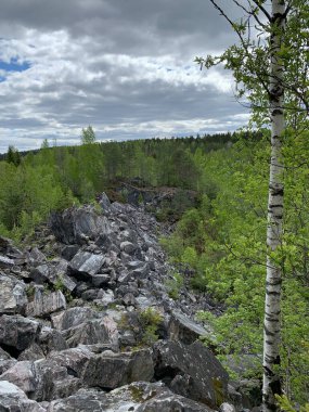 Güneşli bir yaz gününde Ruskeala Dağ Parkı 'ndaki mermer madenciliğinden arta kalan mermer kayalar..