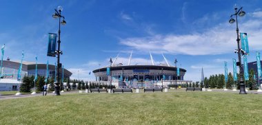 St. Petersburg 'daki Gazprom Stadyumu' nun önündeki çimen ve banklar bulutlu mavi gökyüzüne karşı..