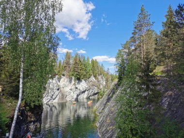 Bir yaz günü Ruskeala Dağ Parkı 'ndaki Mermer Kanyon' un turkuaz sularında yüzen kayalıkların ve teknelerin en üst görüntüsü..