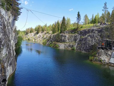 Güneşli bir yaz gününde gökyüzünü ve ağaçları yansıtan Ruskeala Dağ Parkı 'ndaki Mermer Kanyon' un kayaları ve zümrüt suyu..