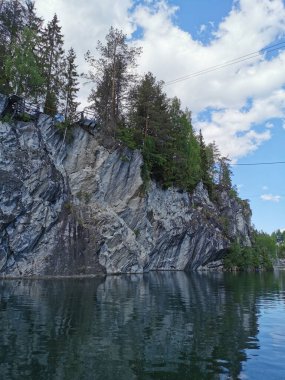 Güneşli bir yaz gününde Ruskeala Dağ Parkı 'ndaki Mermer Kanyon' un suyuna yansıyan mermer parçasının altından bir manzara..