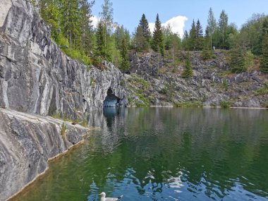 Güneşli bir yaz gününde Ruskeala dağ parkında, mağara suyundan ve ağaçların yetiştiği su basmış Mermer Kanyon 'un bir bölümünden manzara.
