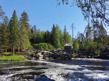 Tokhmayoki Nehri 'nin kıyısında ahşap bir ev bulunan pitoresk şelaleler Karelian doğasıyla çevrilidir..