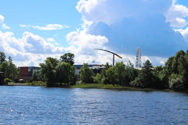 Nehirden ağaçlara ve virüsten dolayı çalışmayan lunapark manzarası. Ayakta duran bir dönme dolap, hareketsiz duran bir roket. St. Petersburg.
