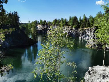 Ruskeala Dağ Parkı 'ndaki Mermer Kanyon' un zümrüt suyunun gözlem güvertesinden gökyüzünün yansıması ve bulutların berrak bir yaz gününde yansıması..