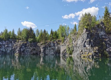 Güneşli bir yaz gününde Ruskeala Dağ Parkı 'ndaki Mermer Kanyon' un kayalık kıyıları, mağaralar ve turkuaz suları manzaralı..