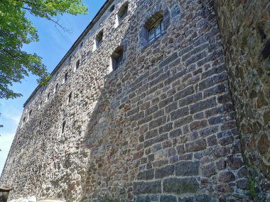 Mavi gökyüzüne karşı Vyborg şehrindeki Vyborg Kalesi 'nin pencereleri olan harici bir taş duvar..