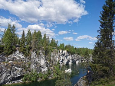 Bir yaz günü Ruskeala Dağ Parkı 'ndaki Mermer Kanyon' un turkuaz sularında yüzen kayalar, mağara ve tekneler görülüyor..