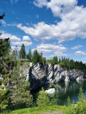 Güneşli bir yaz gününde gökyüzünü ve kayaları yansıtan Ruskeala Dağ Parkı 'ndaki Mermer Kanyon' un kayaları ve zümrüt suyu..