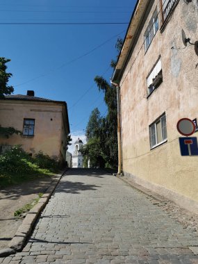 Vyborg şehrinin eski çan kulesi Saat Kulesi 'ne giden kaldırım taşı caddesi mavi gökyüzüne karşı..