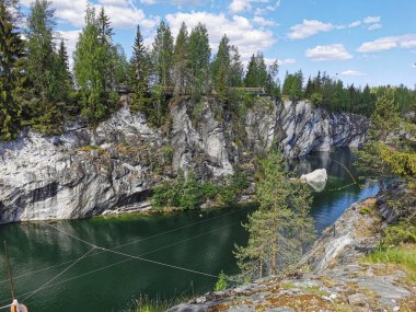 Kayalıkların en üst manzarası, Ruskeala Dağ Parkı 'ndaki Mermer Kanyon' un turkuaz sularında yüzen büyük taş ve kayıklar güneşli bir yaz gününde..