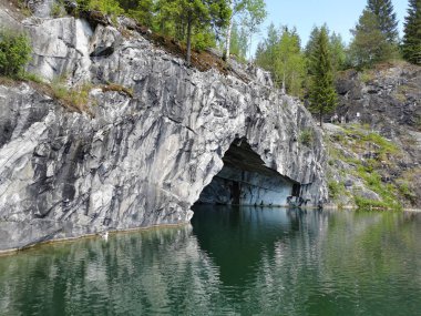 Güneşli bir yaz gününde Ruskeala dağ parkında, mağara suyundan ve ağaçların yetiştiği su basmış Mermer Kanyon 'un bir bölümünden manzara.
