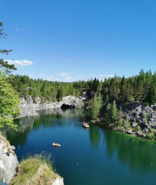 Ruskeala Dağ Parkı 'ndaki Mermer Kanyon' un turkuaz suyunun gözlem güvertesinden gökyüzünün yansıması ve güneşli bir yaz gününde ağaçların görüntüsü..
