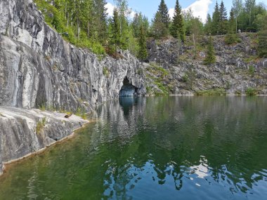 Güneşli bir yaz gününde Ruskeala dağ parkında, mağara suyundan ve ağaçların yetiştiği su basmış Mermer Kanyon 'un bir bölümünden manzara.