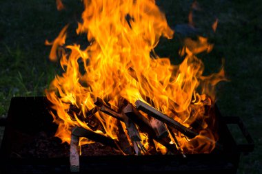 Izgarada dans eden alevler, karanlıkta yanan odun. Kömürlerin pişirilmesi.