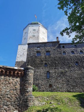 Vyborg Kalesi 'nin duvarları ve Vyborg şehrindeki St. Olaf Kulesi mavi gökyüzüne karşı..