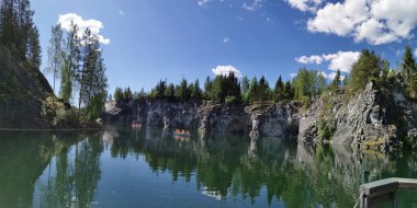 Güneşli bir yaz gününde gökyüzünün, dağların, mağaraların ve bulutların yansımasıyla dağ parkındaki Mermer Kanyon 'un zümrüt suyunun manzarasına bakın..