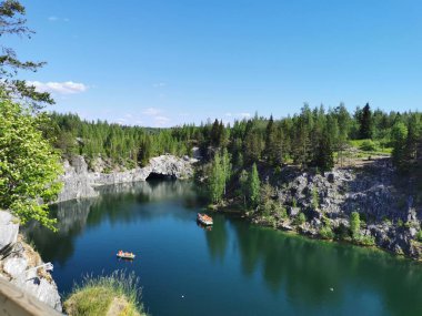 Ruskeala Dağ Parkı 'ndaki Mermer Kanyon' un turkuaz suyunun gözlem güvertesinden gökyüzünün yansıması ve güneşli bir yaz gününde ağaçların görüntüsü..
