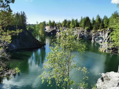 Ruskeala Dağ Parkı 'ndaki Mermer Kanyon' un zümrüt suyunun gözlem güvertesinden gökyüzünün yansıması ve bulutların berrak bir yaz gününde yansıması..
