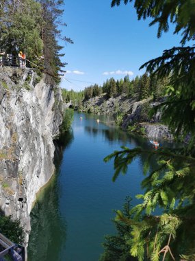Bir yaz günü Ruskeala Dağ Parkı 'ndaki Mermer Kanyon' un turkuaz sularında yüzen kayalıkların, mağaraların ve teknelerin en üst görüntüsü..