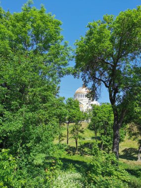 Kronstadt şehrinin Yaz Bahçesi 'ndeki ağaçların arasındaki St. Nicholas Katedrali' nin manzarası bulutsuz bir gökyüzünün arka planında.