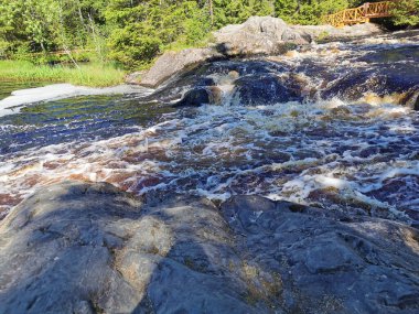 Karelia 'daki Tokhmayoki Nehri' ndeki kahverengi suyla kaynayan şelalenin manzarası ekolojik patikadan