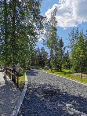 Güneşli bir yaz gününde Ruskeala Dağ Parkı 'ndaki Mermer Kanyon' un etrafında çitli ağaçların arasında bir yürüyüş yolu..