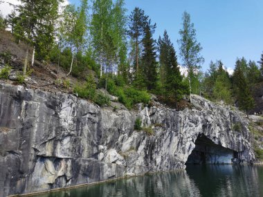 Güneşli bir yaz gününde Ruskeala dağ parkında, mağara suyundan ve ağaçların yetiştiği su basmış Mermer Kanyon 'un bir bölümünden manzara.