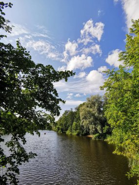 Şehir parkındaki ağaçların arasında bir gölet. Tatilcilerin güneşli bir yaz gününde kayıkla gezdikleri yer..
