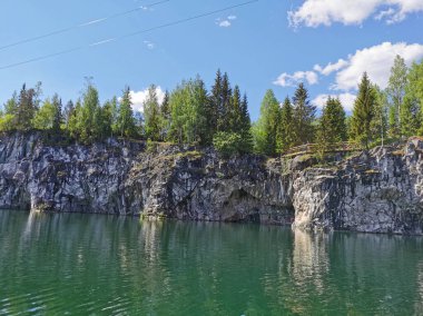 Güneşli bir yaz gününde Ruskeala Dağ Parkı 'ndaki Mermer Kanyon' un kayalık kıyıları, mağaralar ve turkuaz suları manzaralı..
