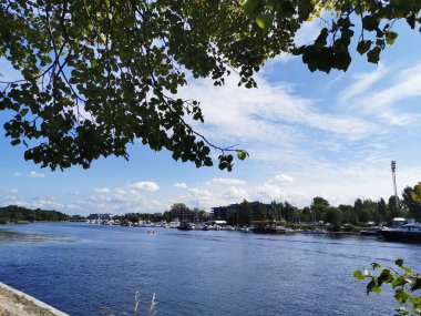 Krestovsky Adası açıklarında duran yatların görüntüsü. Güneşli bir yaz gününde bulutlu mavi gökyüzünün arka planına doğru giden bir tekne görülüyor.